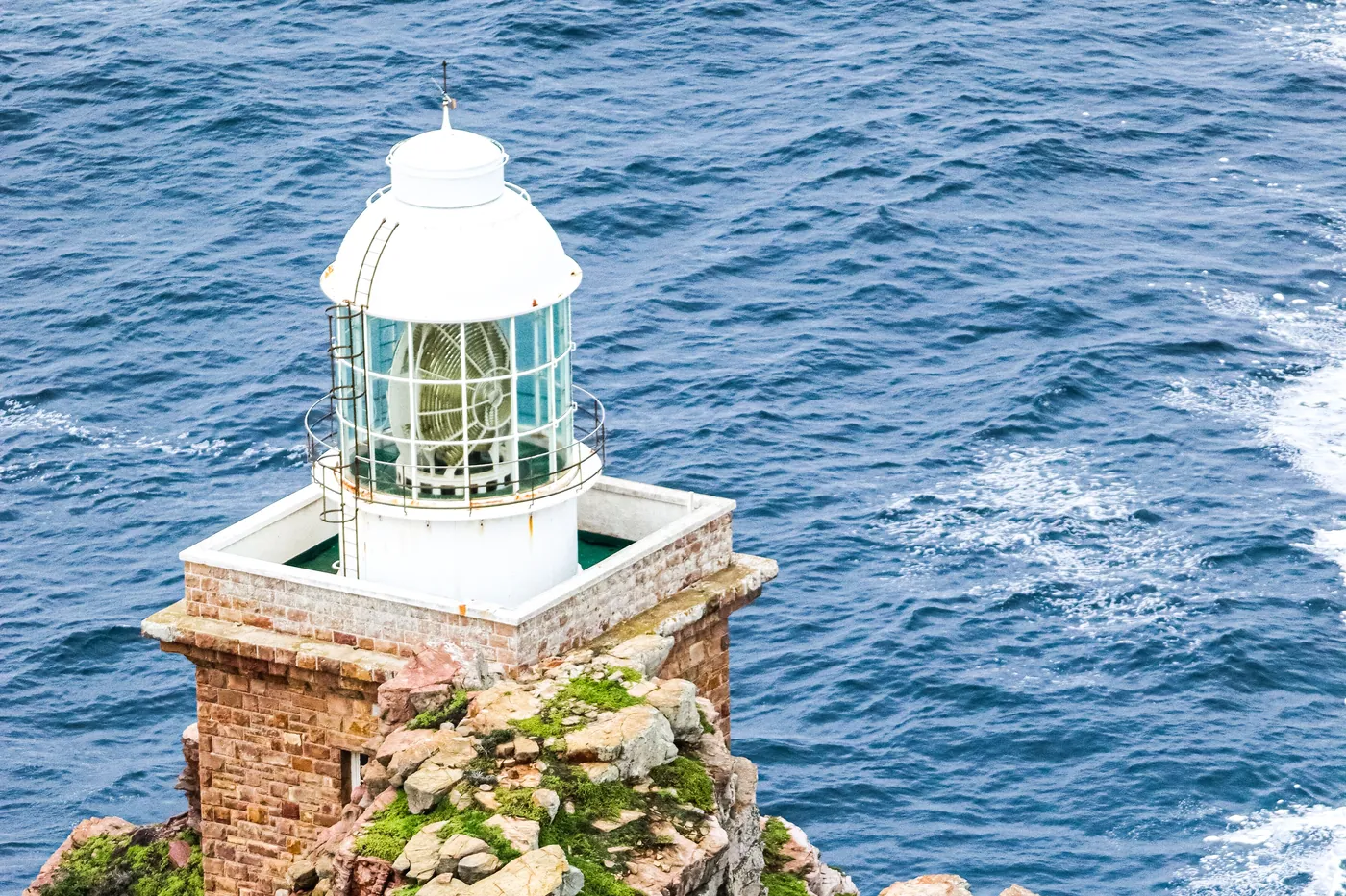 Lighthouse on the rocky headland at Cape Point, seen from above with the open ocean beyond
