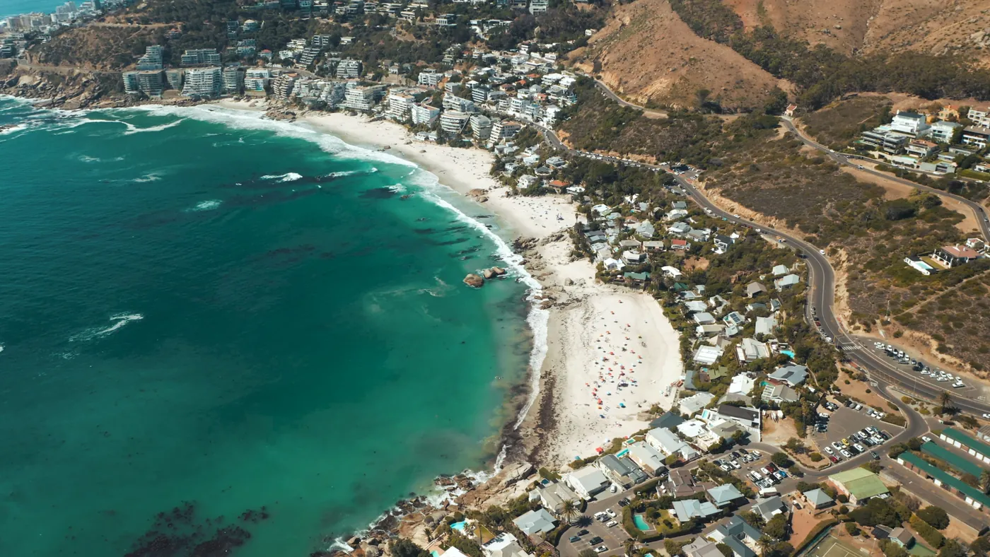 Aerial view of a turquoise bay on the Atlantic seaboard with a white beach and houses on the slope