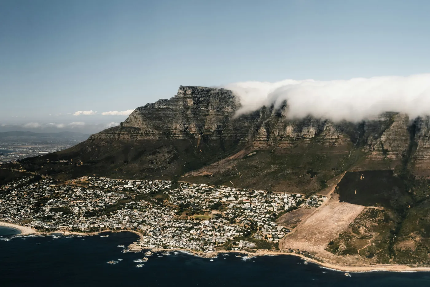 Table Mountain from the air, with cloud spilling over the ridge above the Atlantic seaboard
