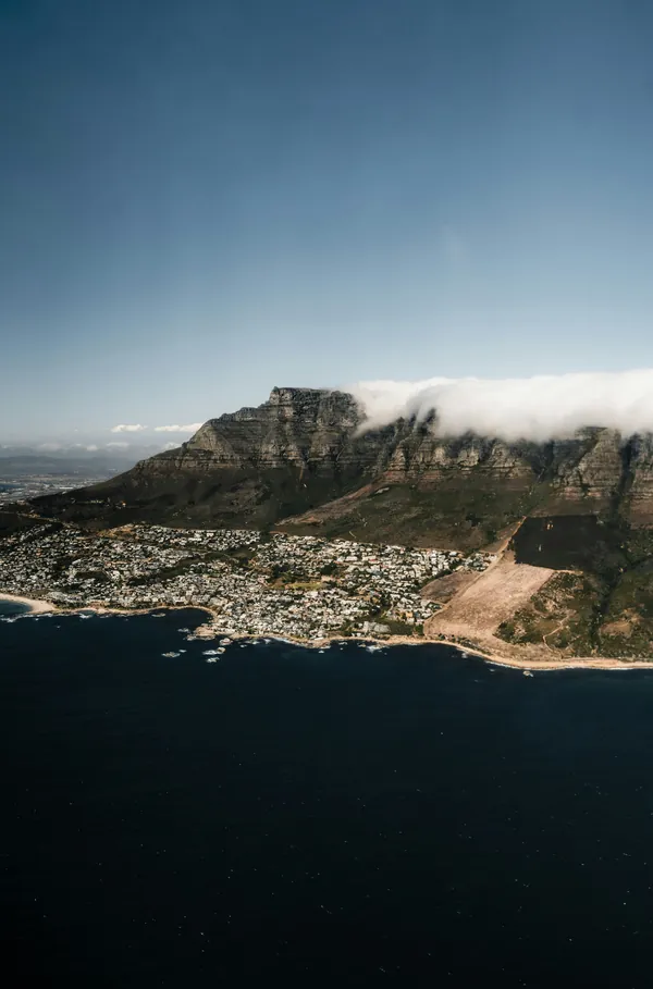 Table Mountain from the air, with cloud spilling over the ridge above the Atlantic seaboard