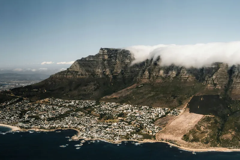 Table Mountain from the air, with cloud spilling over the ridge above the Atlantic seaboard