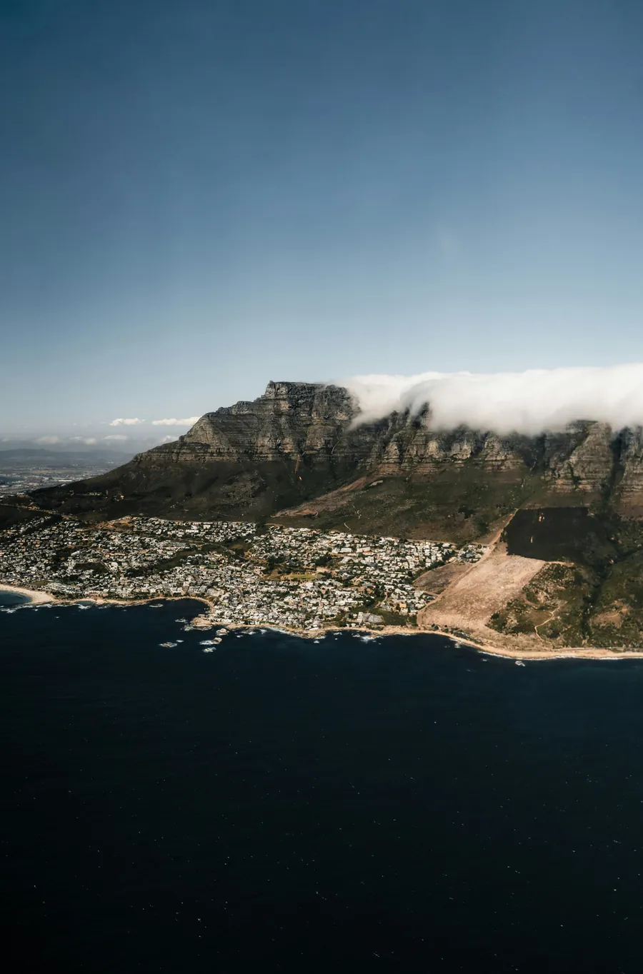 Table Mountain from the air, with cloud spilling over the ridge above the Atlantic seaboard